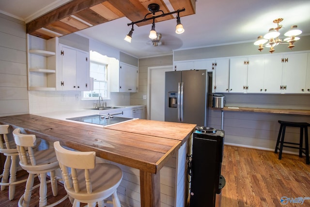 kitchen featuring decorative light fixtures, open shelves, white cabinetry, a sink, and stainless steel fridge