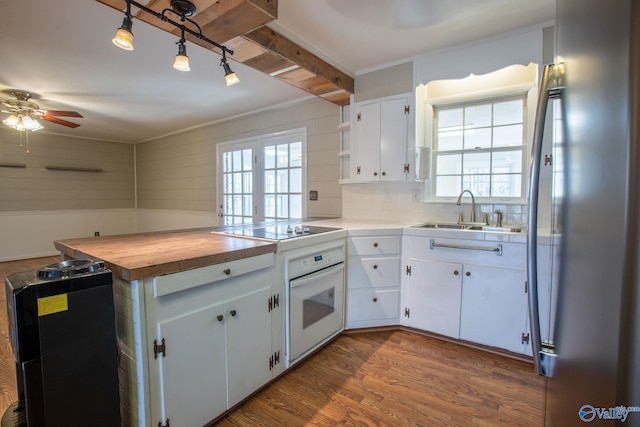 kitchen featuring oven, black electric cooktop, a sink, white cabinetry, and dark wood-style floors