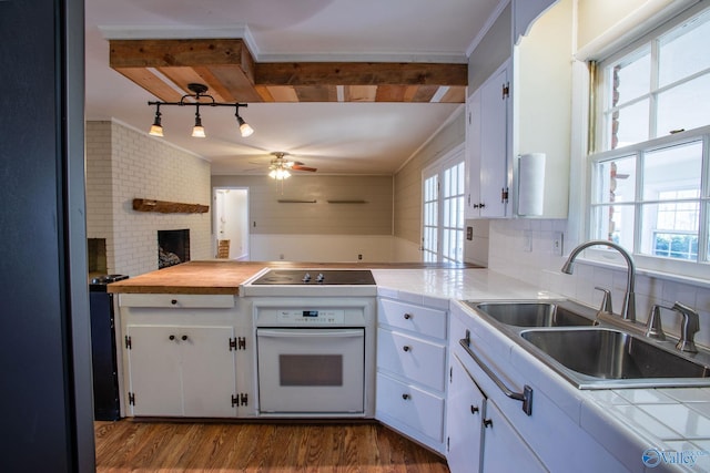 kitchen featuring dark wood-type flooring, oven, black electric cooktop, white cabinetry, and a sink