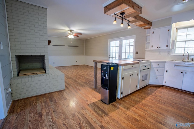 kitchen with open shelves, light countertops, white cabinets, a sink, and wood finished floors