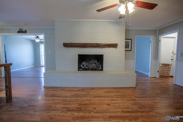 unfurnished living room featuring ceiling fan, a fireplace, dark wood finished floors, and crown molding