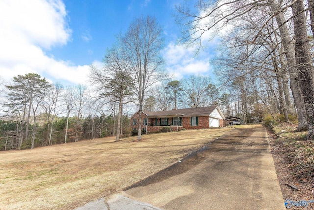 view of front of property with a garage, driveway, brick siding, and a front yard