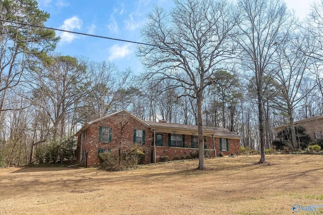 view of front of home featuring a front yard, brick siding, and a chimney