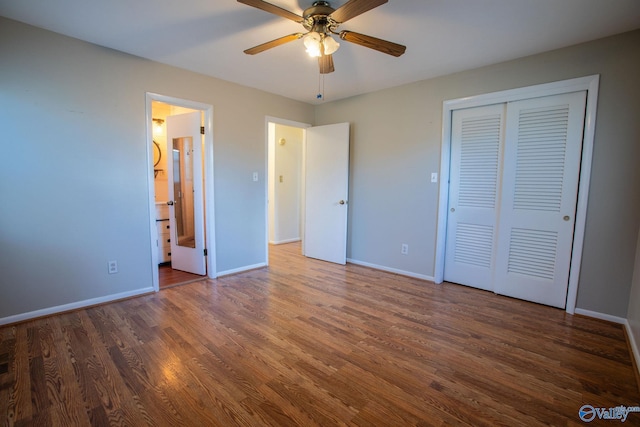 unfurnished bedroom featuring dark wood-type flooring, a closet, ensuite bath, and baseboards