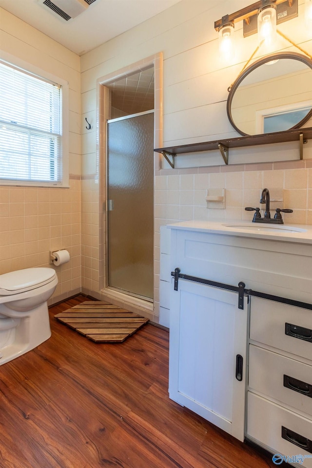 full bathroom featuring a stall shower, wood finished floors, and tile walls