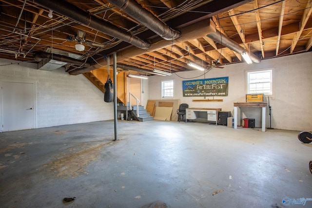 basement featuring concrete block wall and stairs