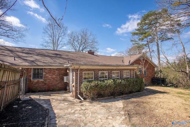 back of property featuring a patio area, brick siding, fence, and a chimney