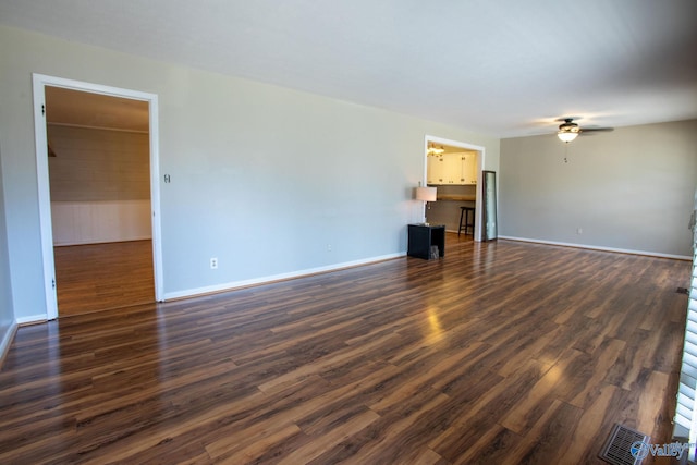 unfurnished living room featuring dark wood-style flooring, a ceiling fan, and baseboards