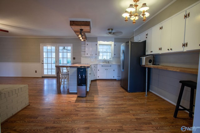 kitchen featuring freestanding refrigerator, white cabinetry, and decorative light fixtures