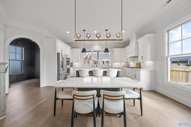 kitchen featuring white cabinetry, hanging light fixtures, tasteful backsplash, a kitchen island, and custom exhaust hood