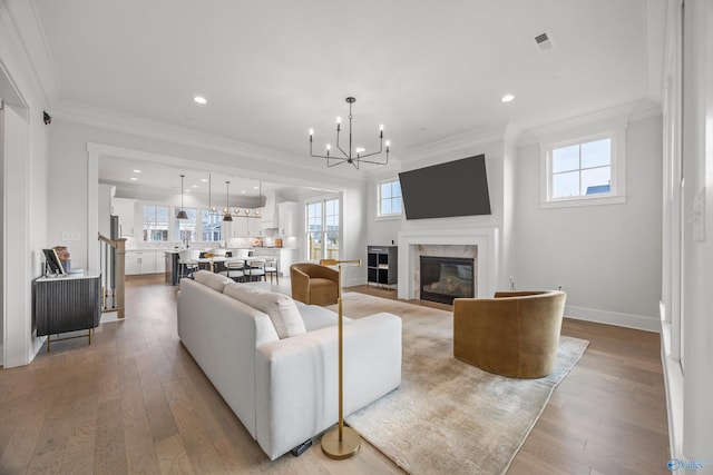 living room with ornamental molding, a premium fireplace, and light wood-type flooring