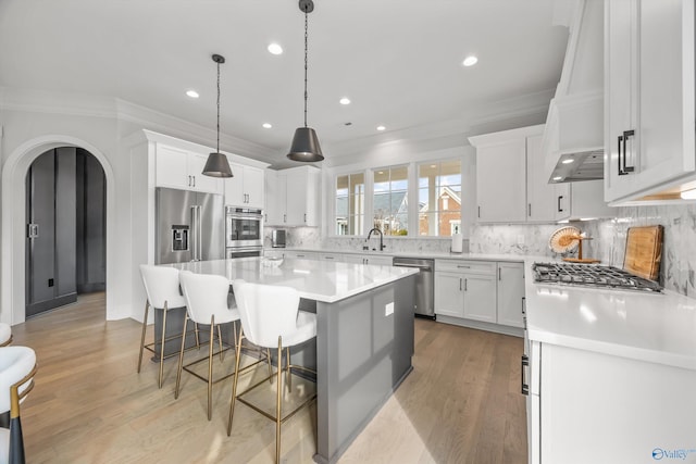 kitchen with sink, a breakfast bar, appliances with stainless steel finishes, white cabinetry, and a kitchen island