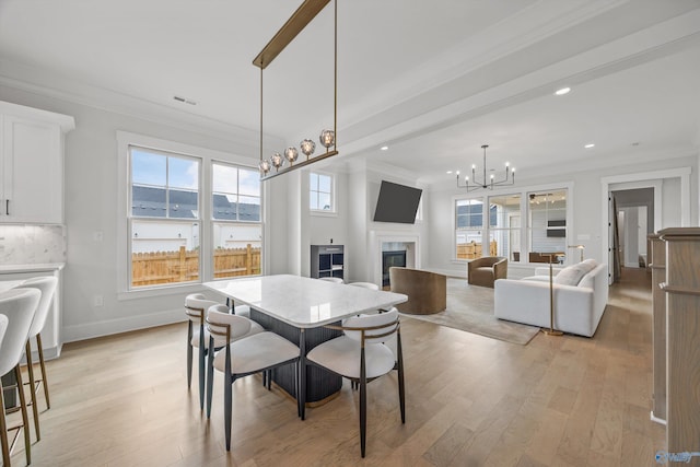 dining area featuring ornamental molding, a chandelier, and light hardwood / wood-style flooring