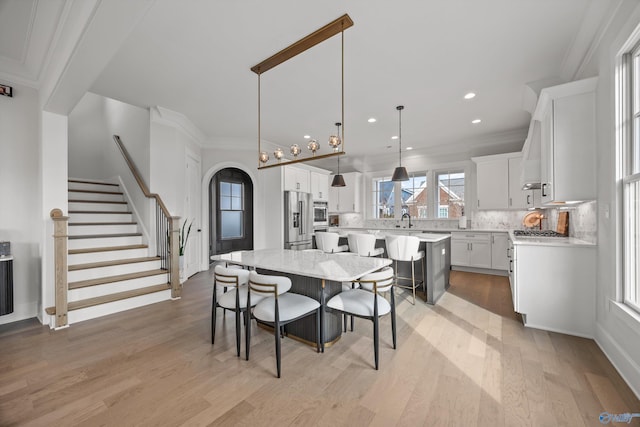 dining space featuring ornamental molding, sink, and light wood-type flooring