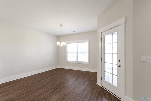 unfurnished room with an inviting chandelier, baseboards, and dark wood-style flooring