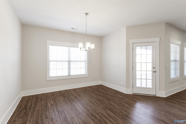 unfurnished dining area with an inviting chandelier, visible vents, baseboards, and dark wood finished floors