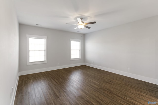 spare room featuring ceiling fan, dark wood finished floors, and baseboards