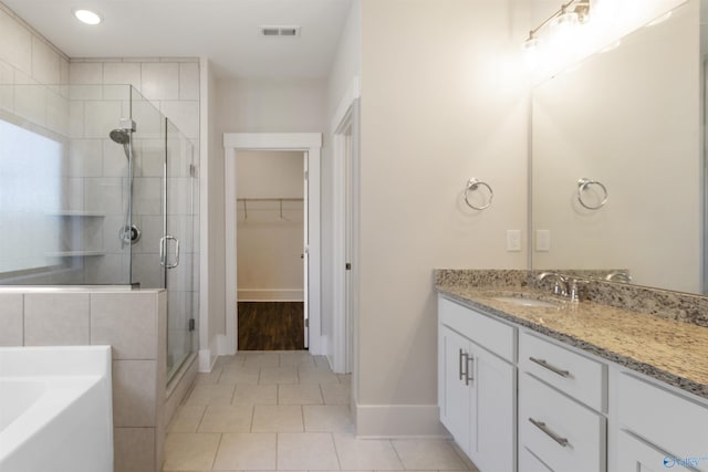 full bathroom with a walk in closet, a garden tub, a stall shower, vanity, and tile patterned flooring