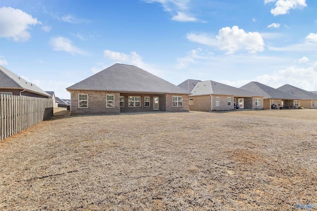 back of property featuring brick siding and fence