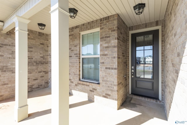 view of exterior entry with covered porch and brick siding