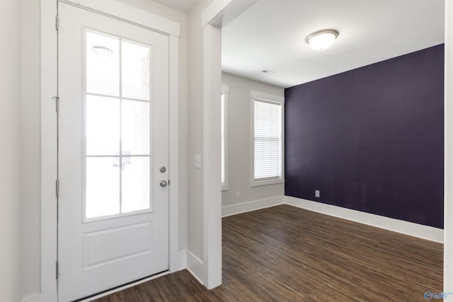 doorway to outside featuring baseboards and dark wood-type flooring