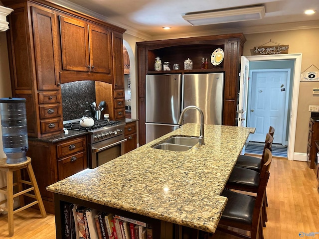 kitchen featuring a kitchen island with sink, stainless steel appliances, sink, and light hardwood / wood-style floors