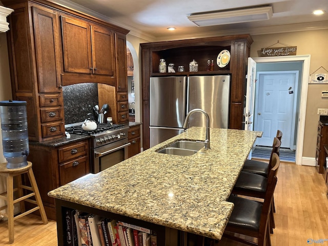 kitchen with a sink, crown molding, light wood-style flooring, stainless steel appliances, and open shelves