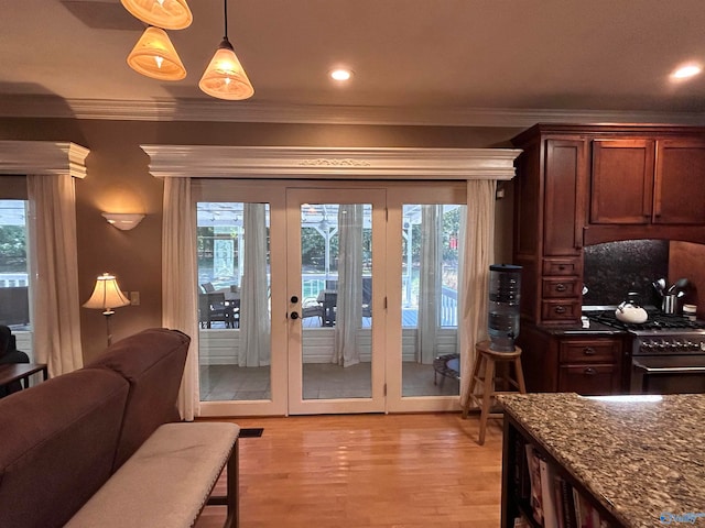 kitchen with high end stainless steel range, light hardwood / wood-style flooring, hanging light fixtures, crown molding, and dark stone counters