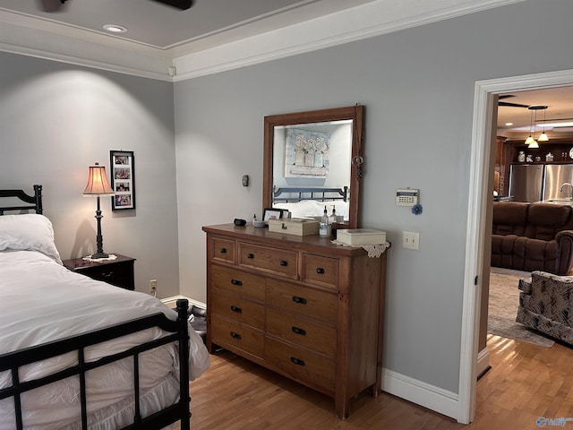 bedroom featuring light wood-style flooring, baseboards, freestanding refrigerator, and ornamental molding