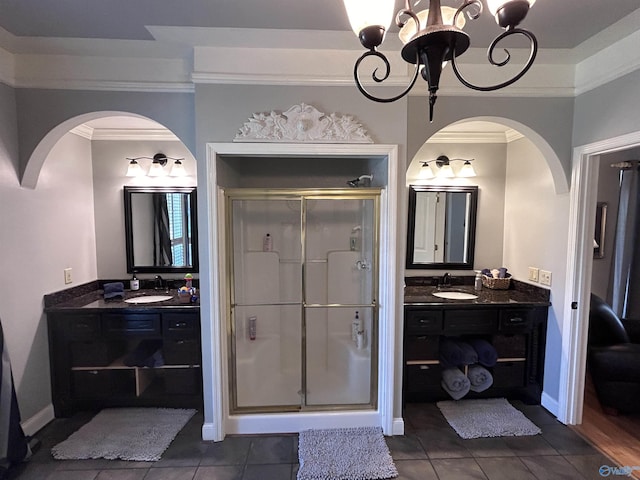 bathroom featuring an inviting chandelier, two vanities, a stall shower, and ornamental molding