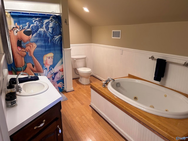 bathroom with hardwood / wood-style flooring, vaulted ceiling, toilet, a bathtub, and vanity