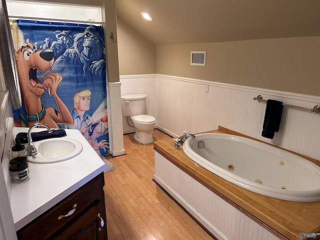 full bathroom with visible vents, toilet, vaulted ceiling, wainscoting, and a tub with jets