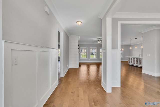 corridor with ornamental molding and light wood-type flooring