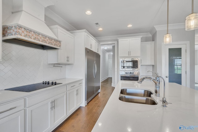 kitchen featuring sink, built in appliances, custom range hood, and white cabinetry