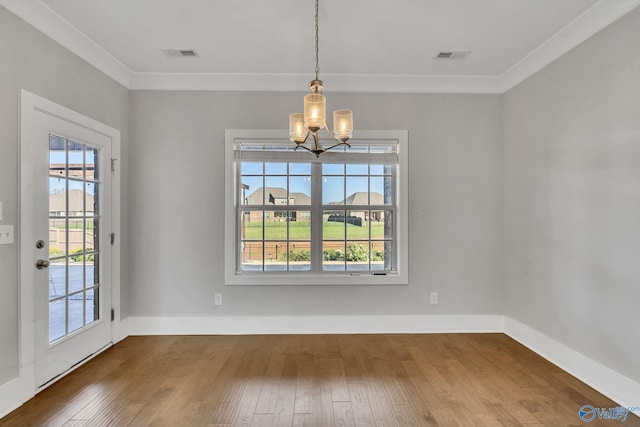 unfurnished dining area featuring a notable chandelier, crown molding, and hardwood / wood-style flooring