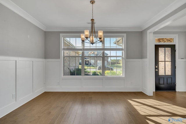 unfurnished dining area with a notable chandelier, hardwood / wood-style floors, and crown molding