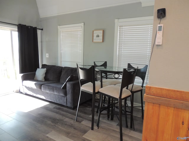 living area featuring vaulted ceiling, crown molding, and wood finished floors