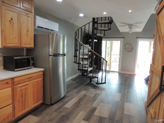 kitchen featuring light countertops, a ceiling fan, a wall unit AC, baseboards, and appliances with stainless steel finishes