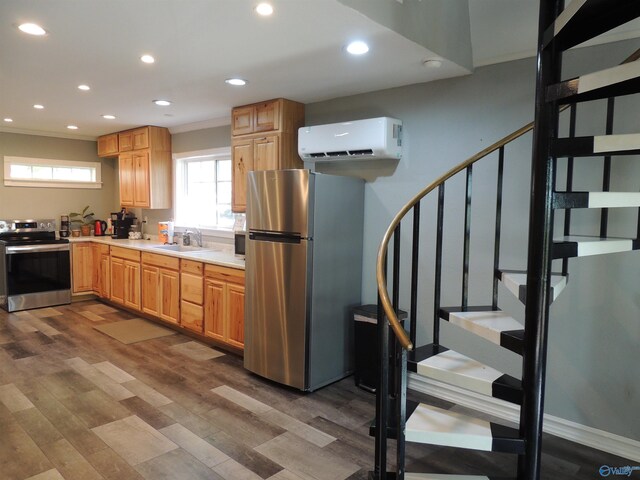 kitchen with recessed lighting, light countertops, wood finished floors, a wall mounted AC, and appliances with stainless steel finishes