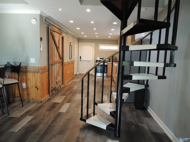 staircase featuring a barn door, wood finished floors, a wainscoted wall, and recessed lighting