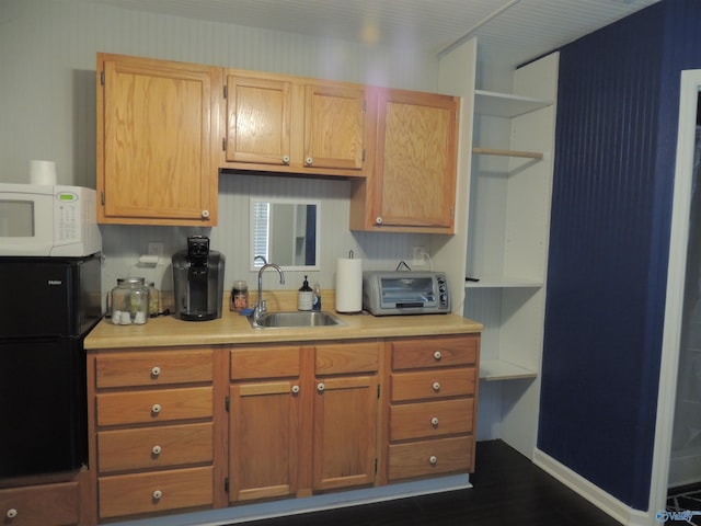 kitchen featuring a sink, a toaster, white microwave, light countertops, and freestanding refrigerator