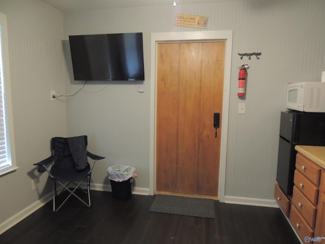 living area featuring baseboards and dark wood-style floors