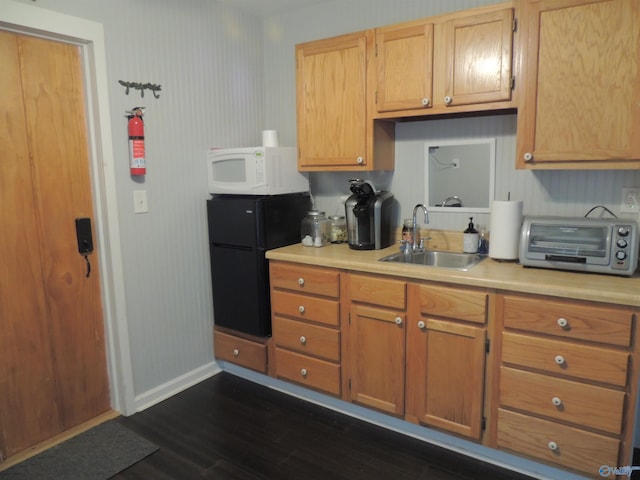 kitchen with a sink, a toaster, white microwave, dark wood finished floors, and freestanding refrigerator
