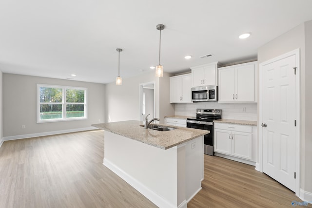 kitchen with stainless steel appliances, a center island with sink, a sink, and white cabinetry