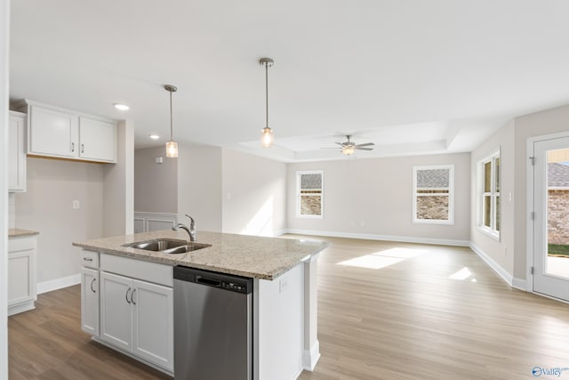 kitchen with dishwasher, light stone counters, a sink, and white cabinetry