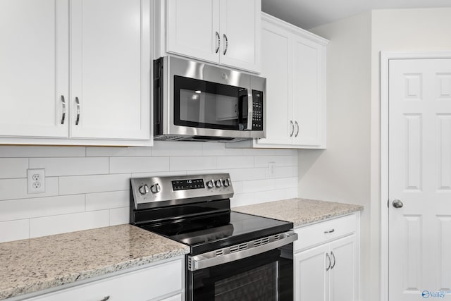 kitchen featuring stainless steel appliances, backsplash, white cabinetry, and light stone countertops