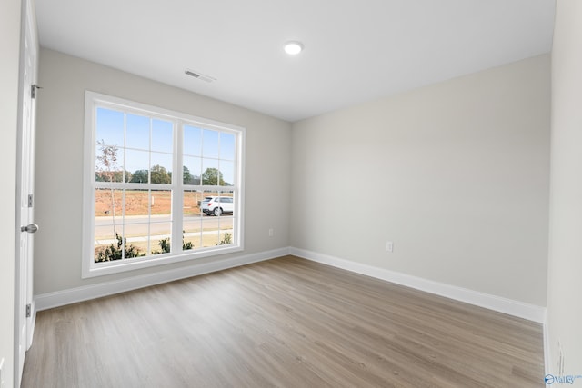 empty room with light wood-type flooring, visible vents, and baseboards