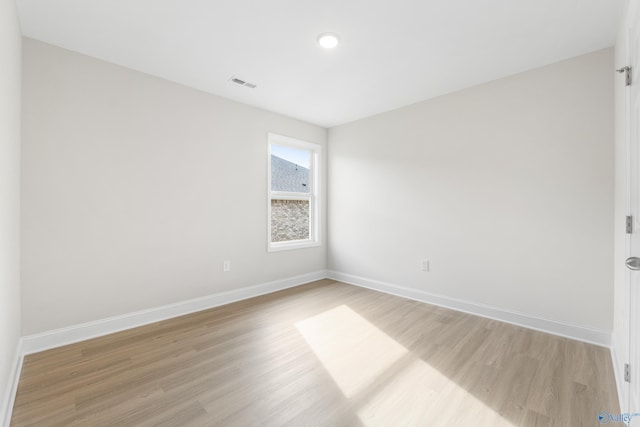 empty room featuring light wood-style floors, visible vents, and baseboards