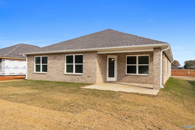 back of property with a patio area, roof with shingles, and a yard