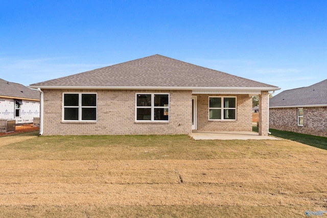 back of property with a patio area, a shingled roof, a yard, and brick siding